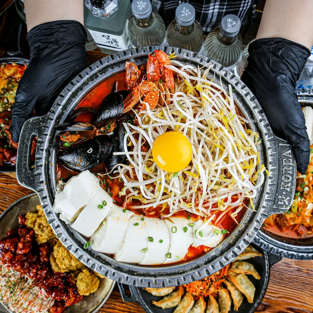 해물순두부찌개 — 붉은 국물에 홍합과 새우를 올리고 콩나물과 노른자, 순두부를 둘렀다